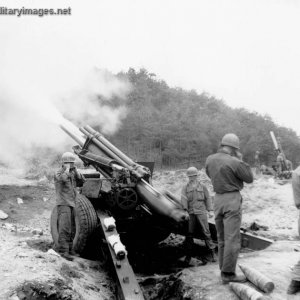 Gun crew fires a 155-mm  howitzer