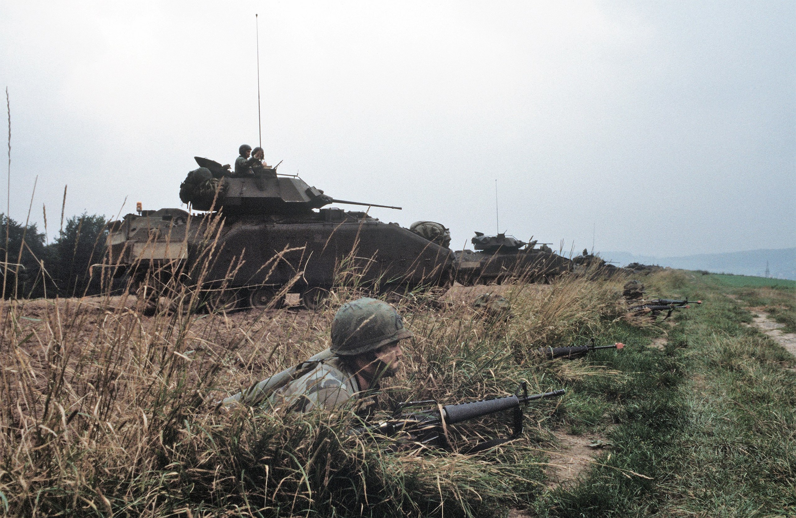 2560px-DA-ST-86-00224_Three_M2_Bradley_advance_through_a_wooded_area_during_Exercise_REFORGER_...jpg