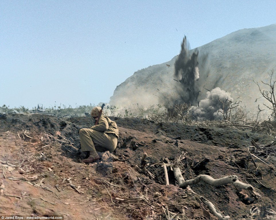 A Marine observes the explosions as shells pound a Japanese position on the island of Iwo Jima...jpg