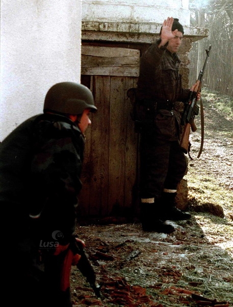A Serbian policeman tells his colleague to take cover during a KLA attack on the village of R...jpeg
