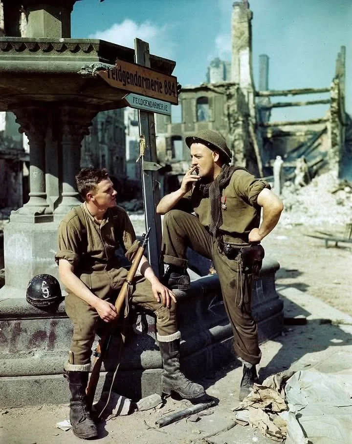 Canadian soldiers A. Lockhart and William Campbell in destroyed Falaise, France, 1944.webp