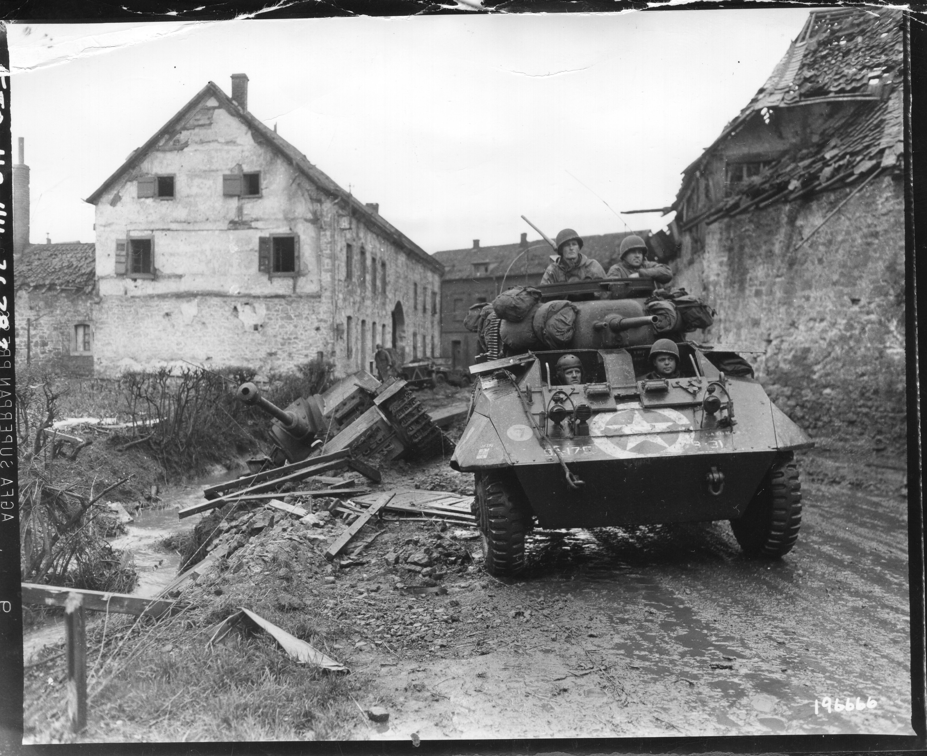 SC_196666_-_An_M8_reconnaissance_armored_car_of_the_30th_Infantry_Div.,_rolls_through_the_stre...jpg