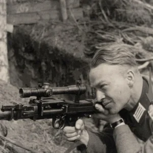 A German soldier taking practice aim with a telescopic sight mounted on an unloaded MG34