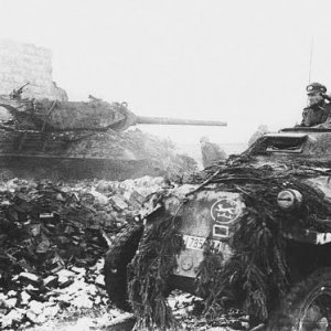 A German half-track passes a knocked out American M10 tank destroyer during the Battle of the Bulge
