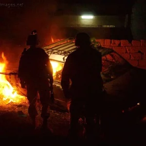 Paratroopers approach a vehicle they destroyed