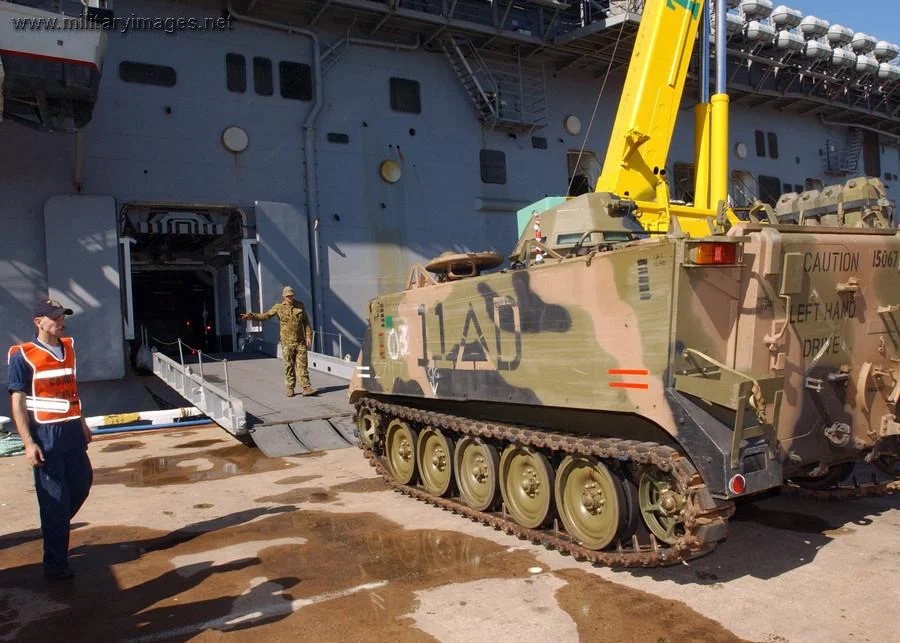 Australian soldier directs the loading of a M113
